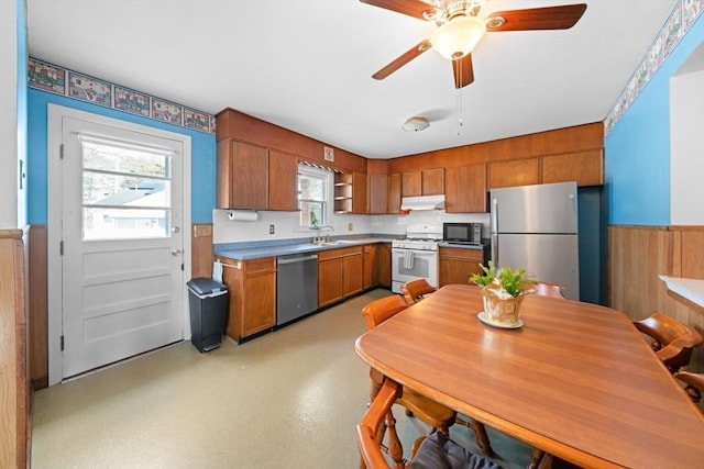 301 Main St, Acushnet, MA 02743 - kitchen with stainless steel appliances, under cabinet range hood, a wainscoted wall, ceiling fan, and brown cabinets