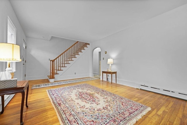 58 Huntington Ave, Dartmouth, MA 02747 - living room with arched walkways, wood finished floors, stairway, and a baseboard radiator
