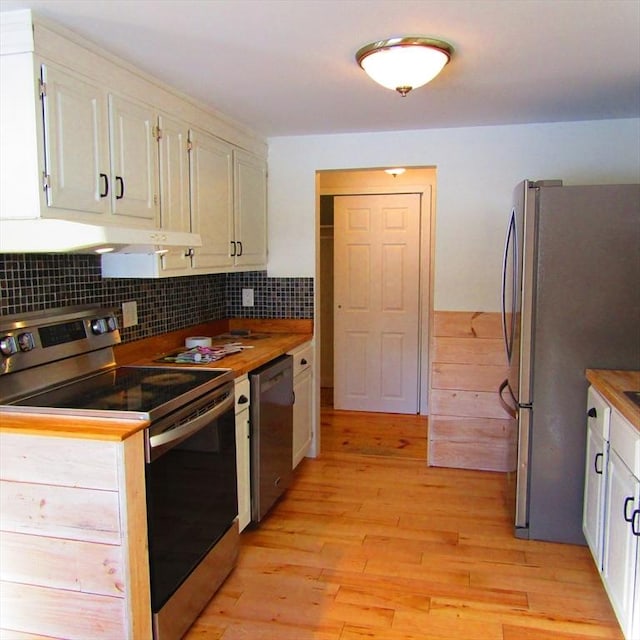 kitchen featuring stainless steel appliances, white cabinets, butcher block countertops, and decorative backsplash