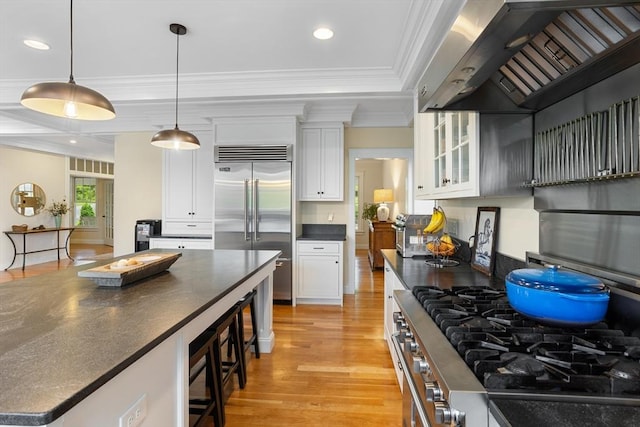 81 Hanover Rd, Carlisle, MA 01741 - kitchen featuring wall chimney exhaust hood, stainless steel appliances, dark countertops, a kitchen breakfast bar, and light wood-style floors