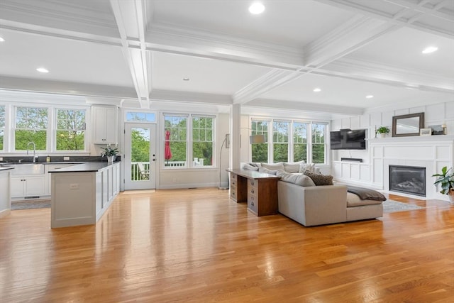 81 Hanover Rd, Carlisle, MA 01741 - living area featuring coffered ceiling, light wood-style floors, a glass covered fireplace, beam ceiling, and crown molding