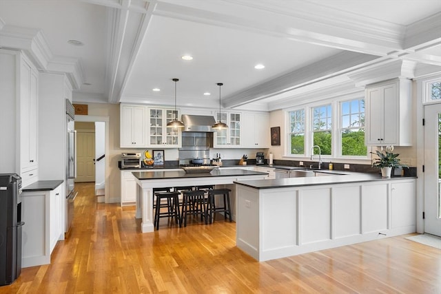 81 Hanover Rd, Carlisle, MA 01741 - kitchen with dark countertops, a peninsula, light wood finished floors, crown molding, and wall chimney range hood