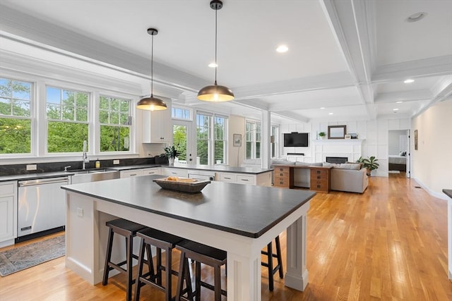 81 Hanover Rd, Carlisle, MA 01741 - kitchen with stainless steel dishwasher, dark countertops, a sink, beamed ceiling, and light wood-style floors