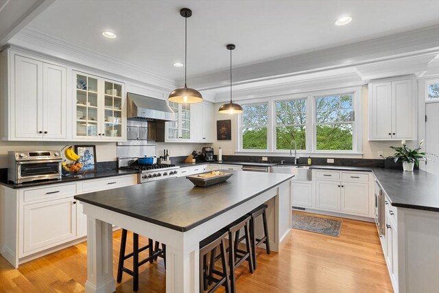 81 Hanover Rd, Carlisle, MA 01741 - kitchen with dark countertops, a sink, wall chimney exhaust hood, plenty of natural light, and crown molding