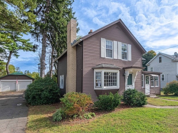 front of property with a front yard, an outdoor structure, and a garage