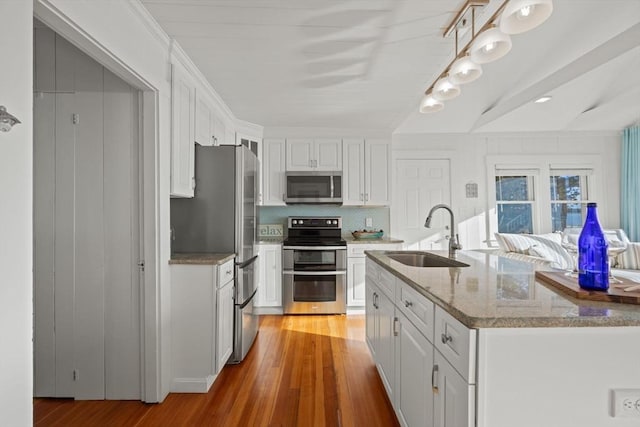 kitchen with appliances with stainless steel finishes, light hardwood / wood-style flooring, white cabinetry, and sink