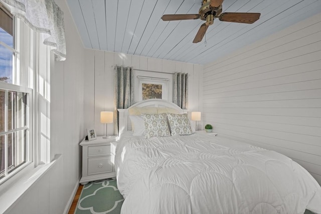 bedroom with ceiling fan and wood walls