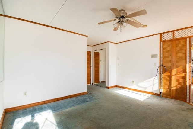 carpeted spare room featuring crown molding, baseboards, and ceiling fan