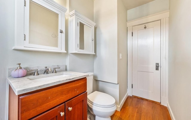 bathroom with wood-type flooring, vanity, and toilet