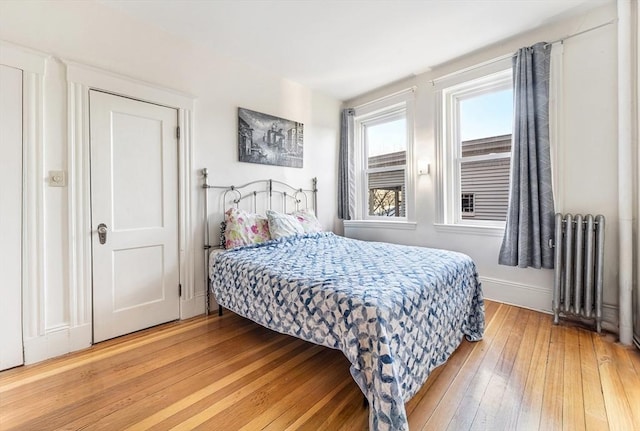 bedroom featuring radiator heating unit and hardwood / wood-style flooring