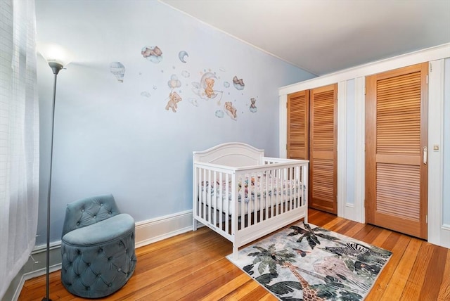 bedroom featuring a crib, wood-type flooring, and a closet