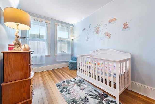 bedroom with wood-type flooring and a nursery area