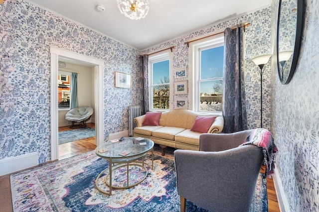 living room with ornamental molding, wood-type flooring, and an inviting chandelier