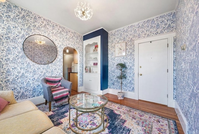 living room featuring a chandelier, crown molding, built in features, and wood-type flooring