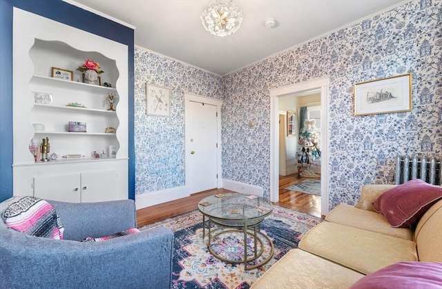 living room with hardwood / wood-style floors, built in features, crown molding, and a notable chandelier