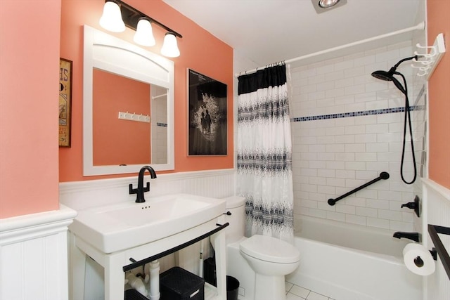 bathroom with a sink, toilet, wainscoting, and shower / bath combination with curtain