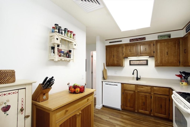 kitchen featuring white appliances, visible vents, wood finished floors, light countertops, and a sink