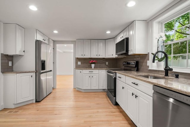 443 Great Plain Ave, Needham, MA 02492 - kitchen featuring appliances with stainless steel finishes, a sink, white cabinetry, tasteful backsplash, and recessed lighting
