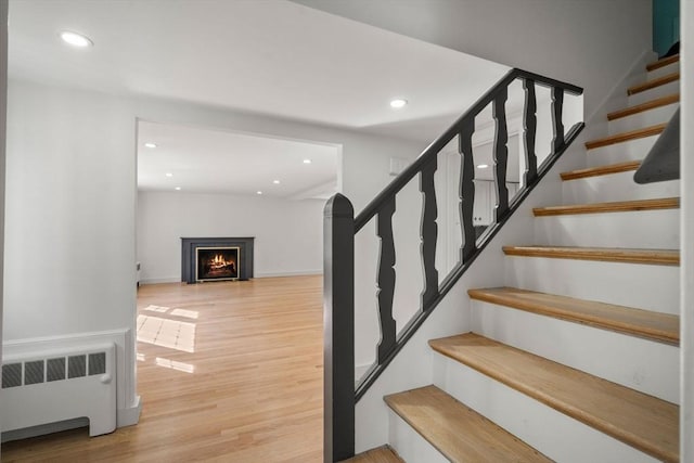 443 Great Plain Ave, Needham, MA 02492 - stairs featuring radiator heating unit, wood finished floors, recessed lighting, a warm lit fireplace, and baseboards