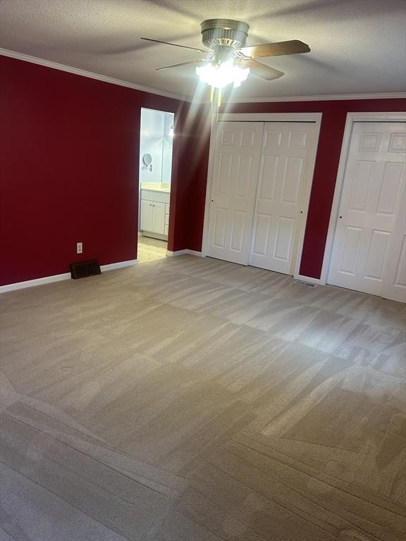 56 Granby Hts Unit 56, Granby, MA 01033 - unfurnished bedroom with carpet floors, baseboards, crown molding, two closets, and ceiling fan