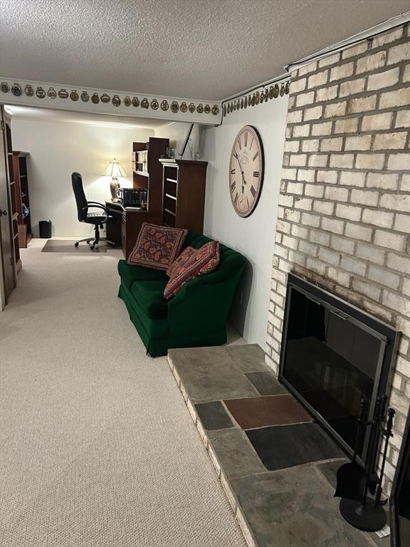 56 Granby Hts Unit 56, Granby, MA 01033 - carpeted living area featuring a brick fireplace, a textured ceiling, and an office area