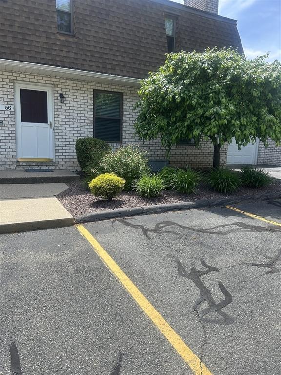 56 Granby Hts Unit 56, Granby, MA 01033 - view of property exterior featuring roof with shingles, brick siding, uncovered parking, mansard roof, and a chimney
