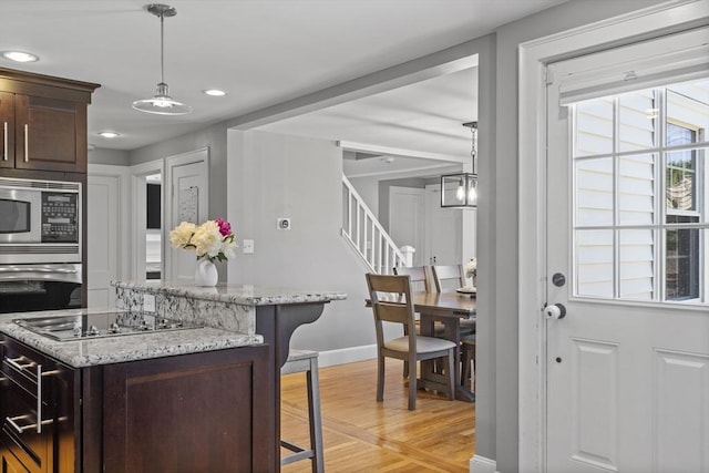 12 Willow St, Wakefield, MA 01880 - kitchen featuring appliances with stainless steel finishes, dark brown cabinetry, light wood finished floors, a breakfast bar area, and a center island