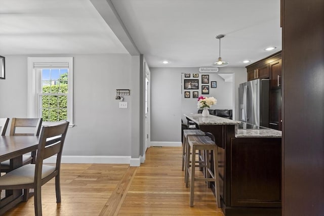 12 Willow St, Wakefield, MA 01880 - kitchen featuring stainless steel fridge, dark brown cabinets, light wood-type flooring, recessed lighting, and a breakfast bar area