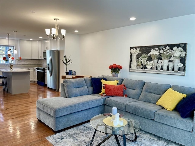 living room with recessed lighting, hardwood / wood-style floors, and an inviting chandelier