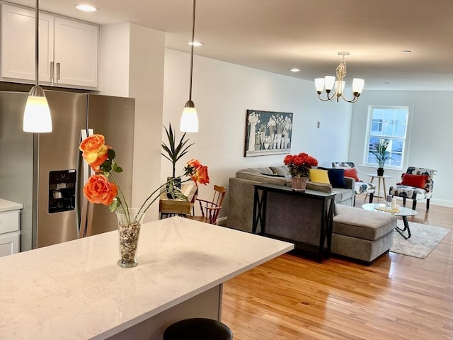 kitchen with a notable chandelier, light wood finished floors, open floor plan, white cabinetry, and stainless steel fridge with ice dispenser