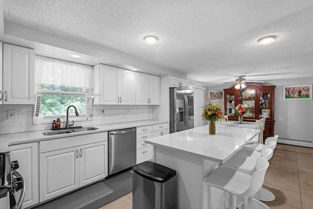 163 Lockland Ave, Framingham, MA 01701 - kitchen with appliances with stainless steel finishes, a sink, a textured ceiling, a kitchen bar, and white cabinetry