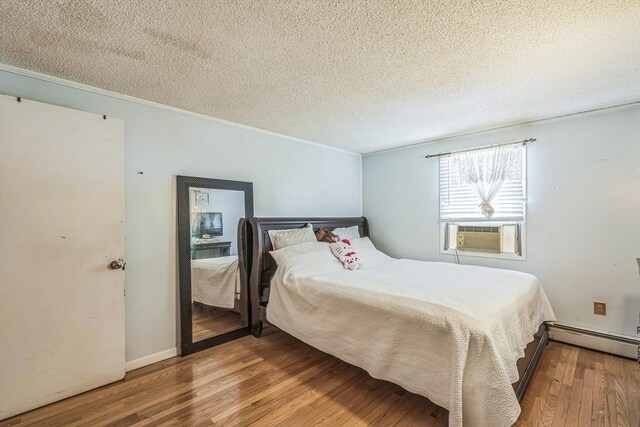 163 Lockland Ave, Framingham, MA 01701 - bedroom with baseboard heating, cooling unit, wood finished floors, a textured ceiling, and crown molding