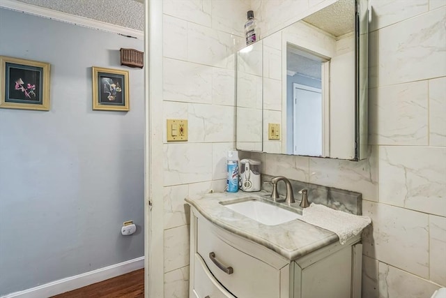 163 Lockland Ave, Framingham, MA 01701 - bathroom with vanity, a textured ceiling, tile walls, crown molding, and wood finished floors