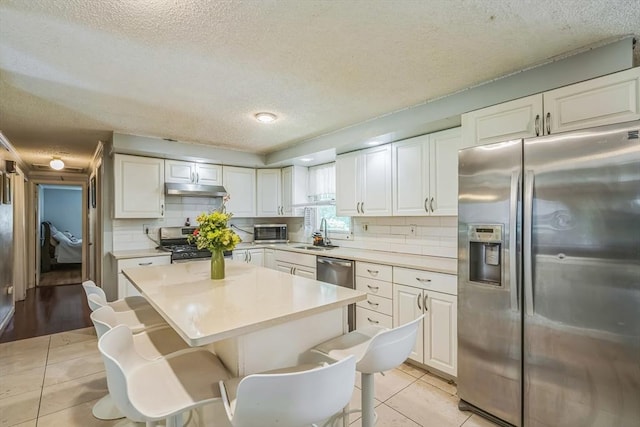163 Lockland Ave, Framingham, MA 01701 - kitchen featuring stainless steel appliances, under cabinet range hood, a textured ceiling, a sink, and light tile patterned floors