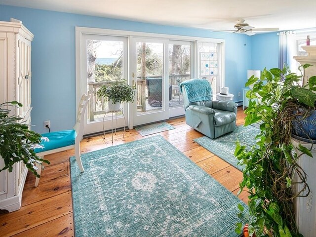 sitting room featuring ceiling fan, wood-type flooring, and a wealth of natural light