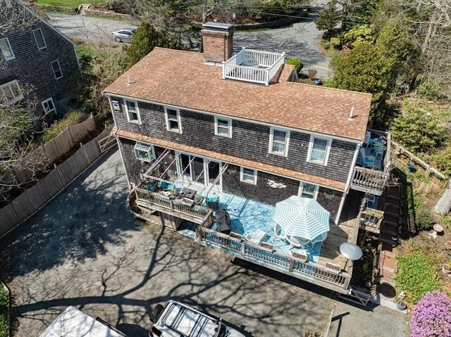 rear view of house with a shingled roof, fence, a chimney, and a deck