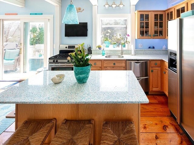 kitchen with appliances with stainless steel finishes, a sink, light wood-style floors, a breakfast bar area, and a center island