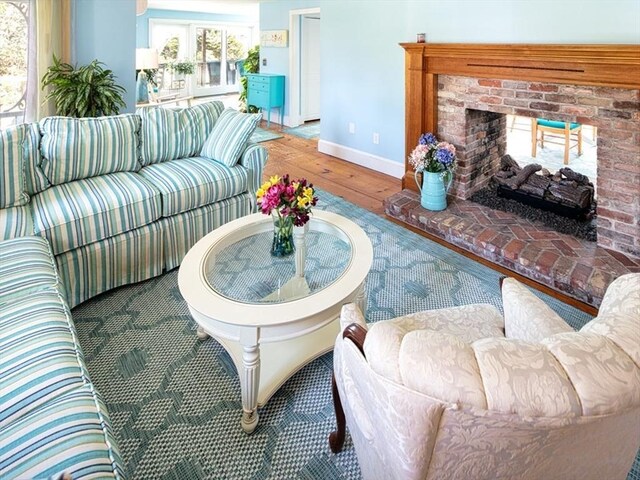 living room with wood-type flooring, baseboards, and a brick fireplace