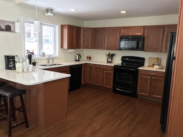 kitchen with dark wood finished floors, a sink, a peninsula, and black appliances