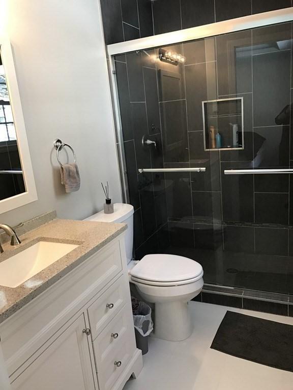 full bath with toilet, vanity, and a shower stall