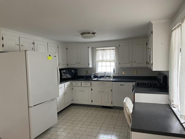 kitchen featuring white cabinets, a sink, dark countertops, and white appliances