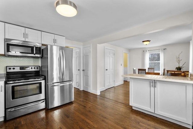 kitchen with dark wood-type flooring, white cabinetry, appliances with stainless steel finishes, and tasteful backsplash