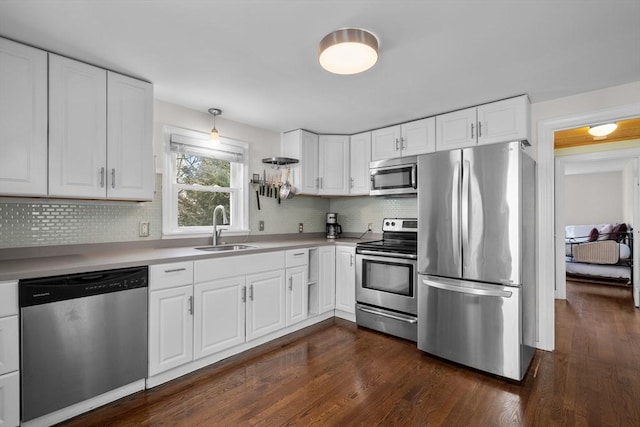 kitchen featuring appliances with stainless steel finishes, decorative backsplash, a sink, and dark wood-type flooring