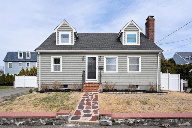 cape cod home featuring a front yard, fence, a shingled roof, and entry steps