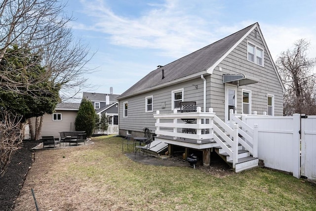 rear view of house featuring a lawn, a deck, fence, and roof with shingles