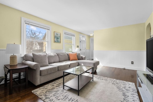 living room featuring a baseboard heating unit, dark wood finished floors, and a wainscoted wall