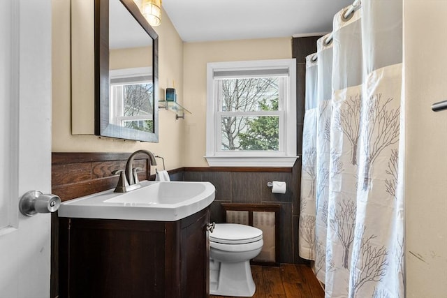 bathroom with wainscoting, curtained shower, wood finished floors, vanity, and toilet