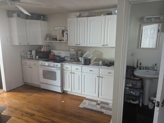 kitchen featuring white cabinets, white gas stove, hardwood / wood-style flooring, and sink