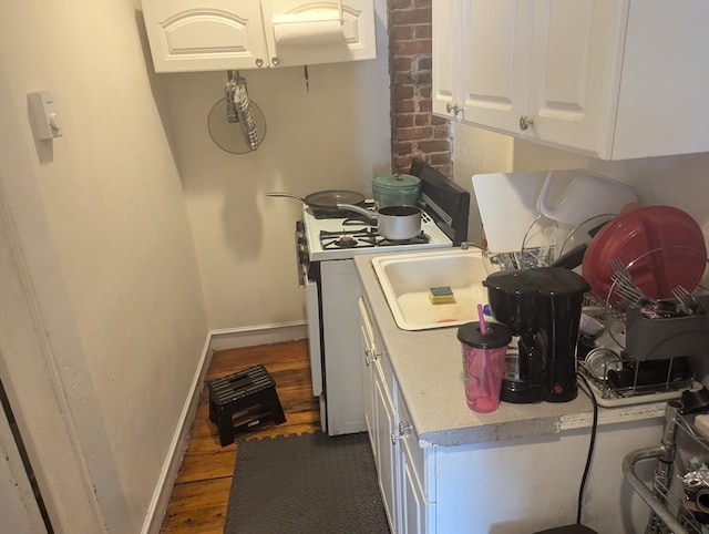 kitchen with white range with gas stovetop, dark wood-type flooring, and white cabinets