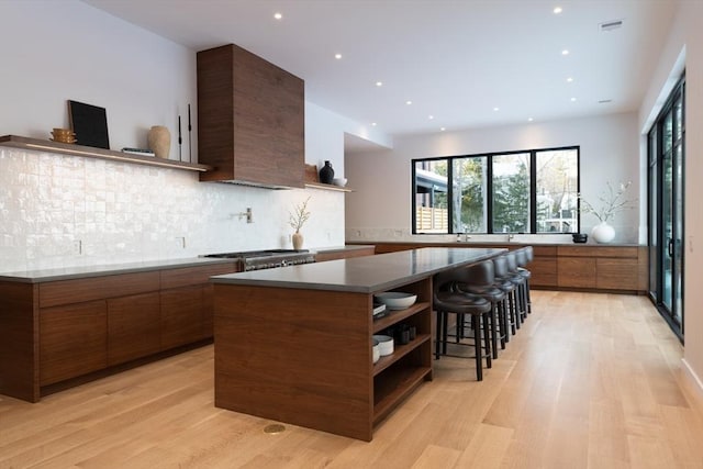 kitchen with open shelves, a spacious island, backsplash, light wood-style floors, and modern cabinets